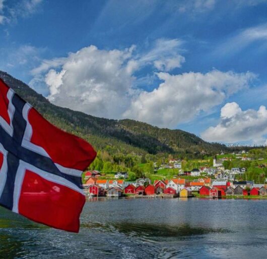 Titelbild-Faszination-Norwegen-Norwegische-Fahne-mit-Blick-auf-Solvorn-Norwegen-Nordlandblog-990x556-1